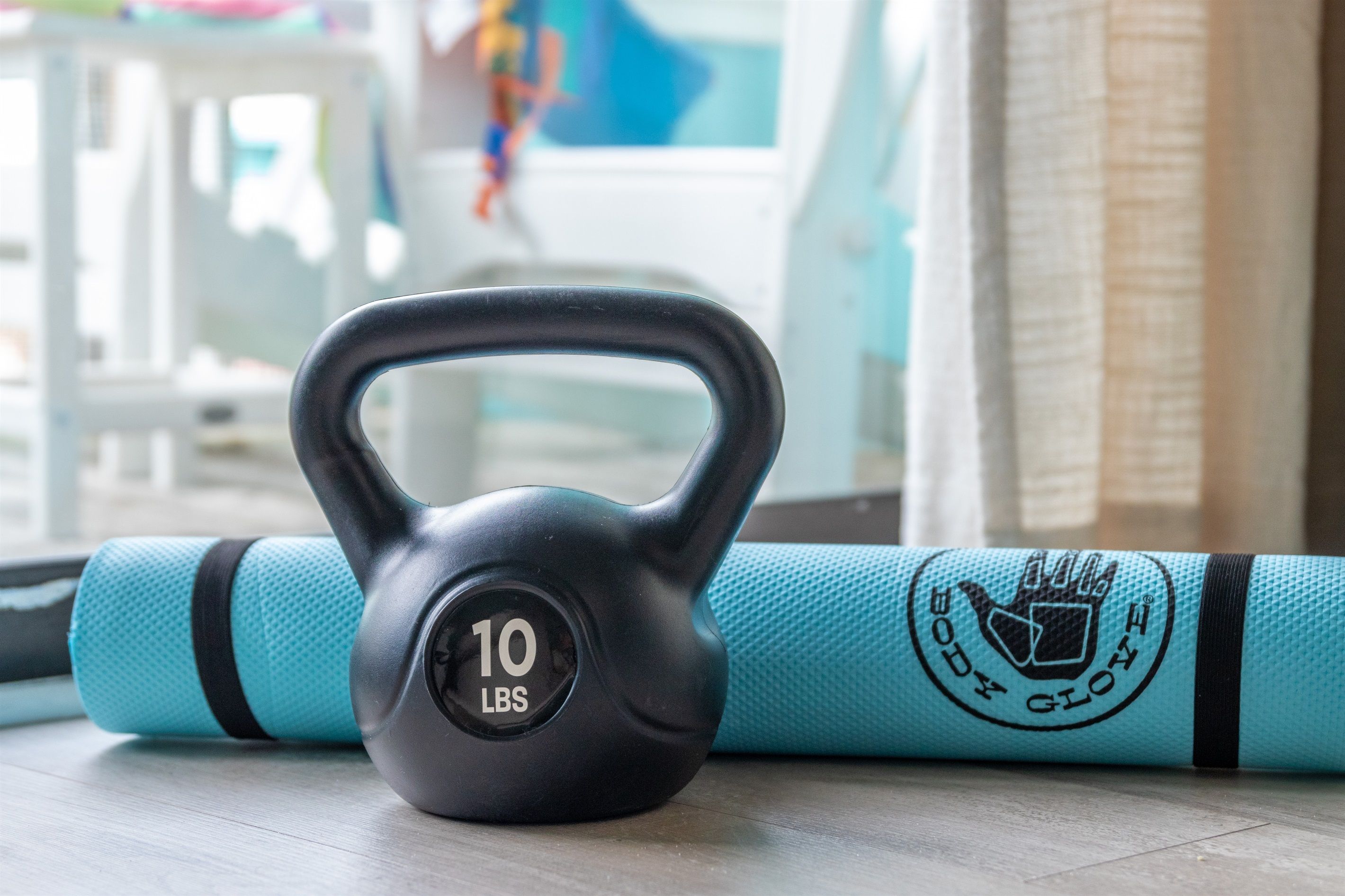 A kettlebell and a yoga mat on a wooden floor.