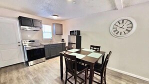 A compact kitchen with modern appliances, a dining table with four chairs, and a wall clock. - Luxury Apartment Suite 5 (El Paso)
