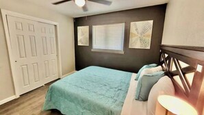 A bedroom with a bed, a ceiling fan, a window with blinds, and a door. - Luxury Apartment Suite 5 (El Paso)