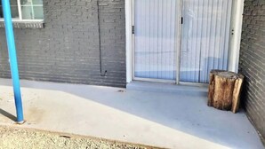 A building with a grey brick exterior, a large sliding glass door, and a small window. - Luxury Apartment Suite 5 (El Paso)