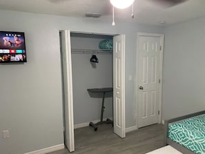 A bedroom with a bed, a closet, and a desk.