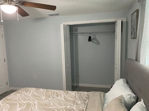 Une chambre à coucher avec un lit, une armoire et un ventilateur de plafond.