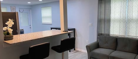 Una cocina moderna con barra, sofá y mesa de comedor.
