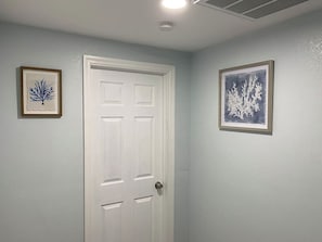 A white door with a keyhole, flanked by two framed artworks on the walls.