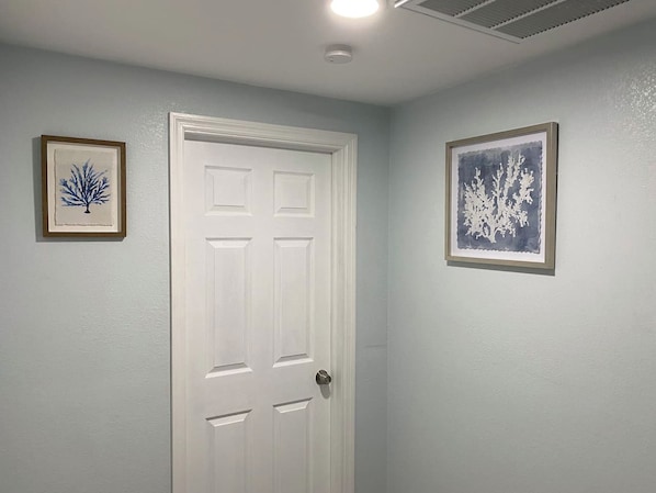 A white door with a keyhole, flanked by two framed artworks on the walls.