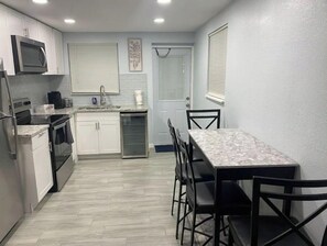 Compact kitchen with modern appliances, oven, and dining area.