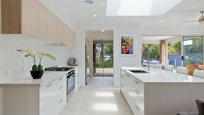 Et moderne køkken med hvide skabe, en central ø og udsigt til det fri.