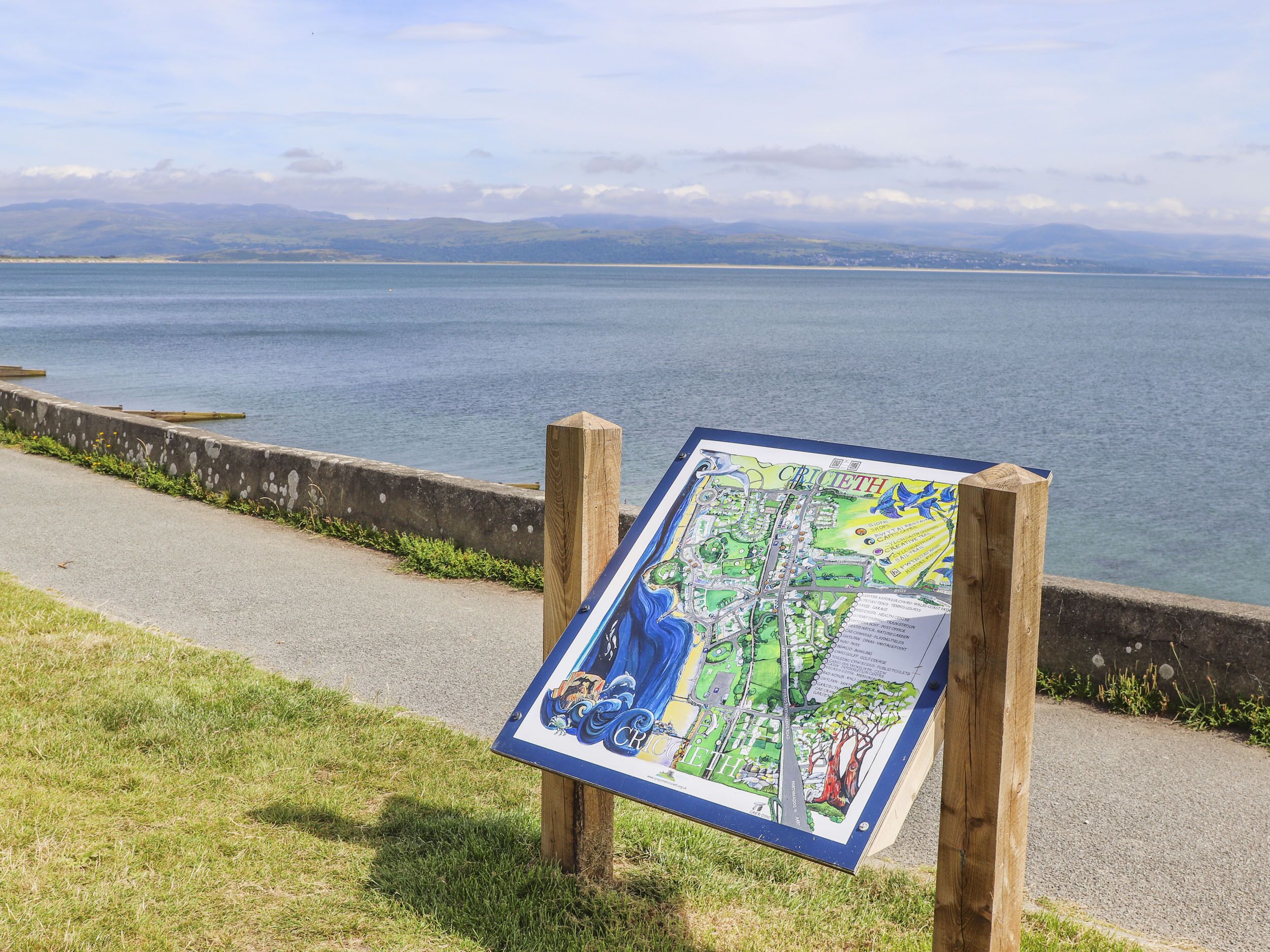 A map on a wooden post by a waterfront path.