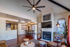 A spacious living room with a fireplace, a ceiling fan, and a dining area.