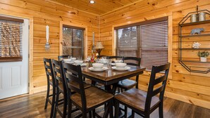 Une salle à manger aux murs lambrés, avec une table dressée pour quatre personnes, entourée de chaises.