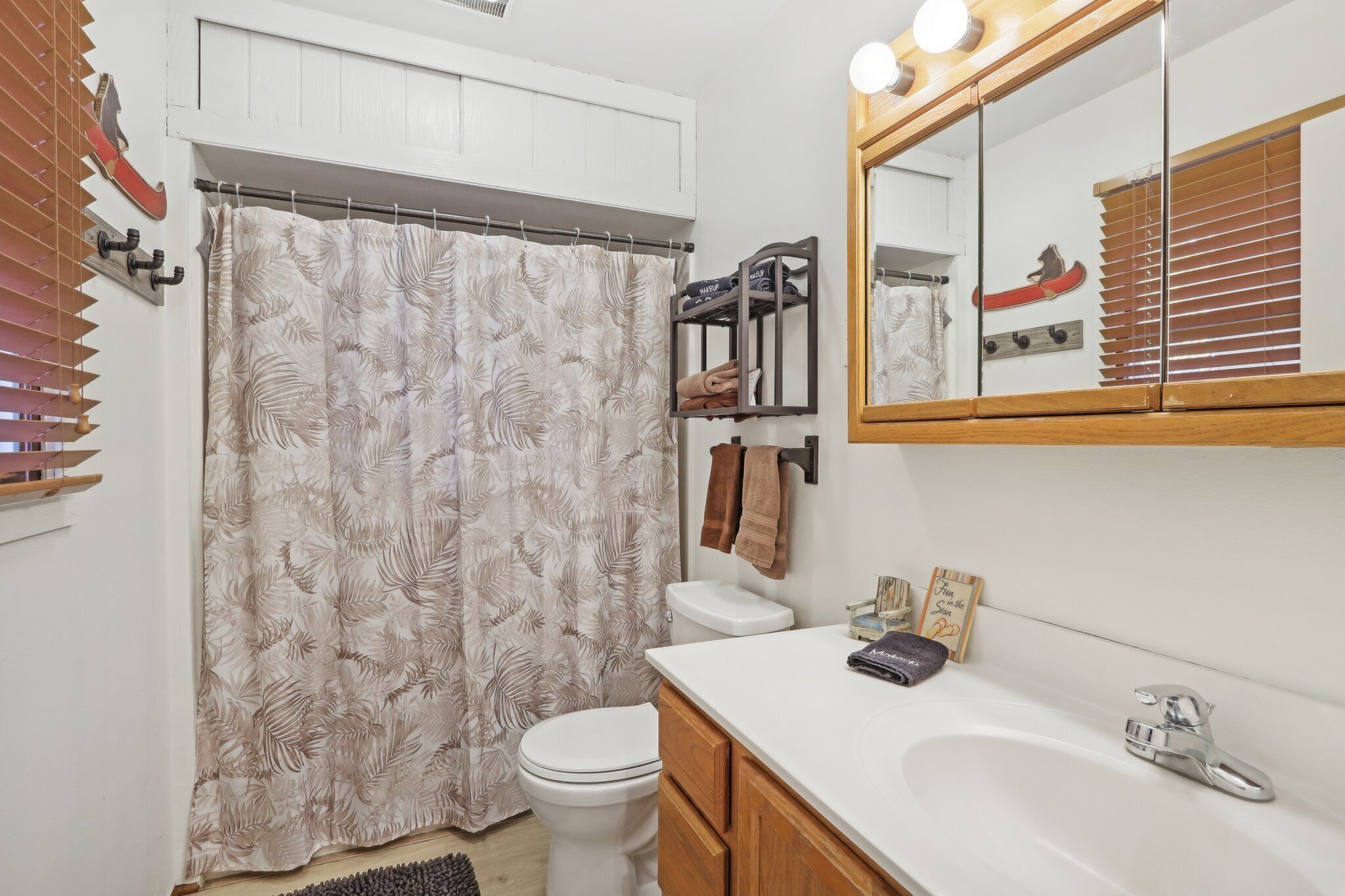 A bathroom with a toilet, a sink, a mirror, and a shower curtain.