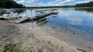 A dock with boats and a covered area by a calm lake. - Family Lakefront Cabin! Hot Tub, Arcades & Dock (Wautoma)
