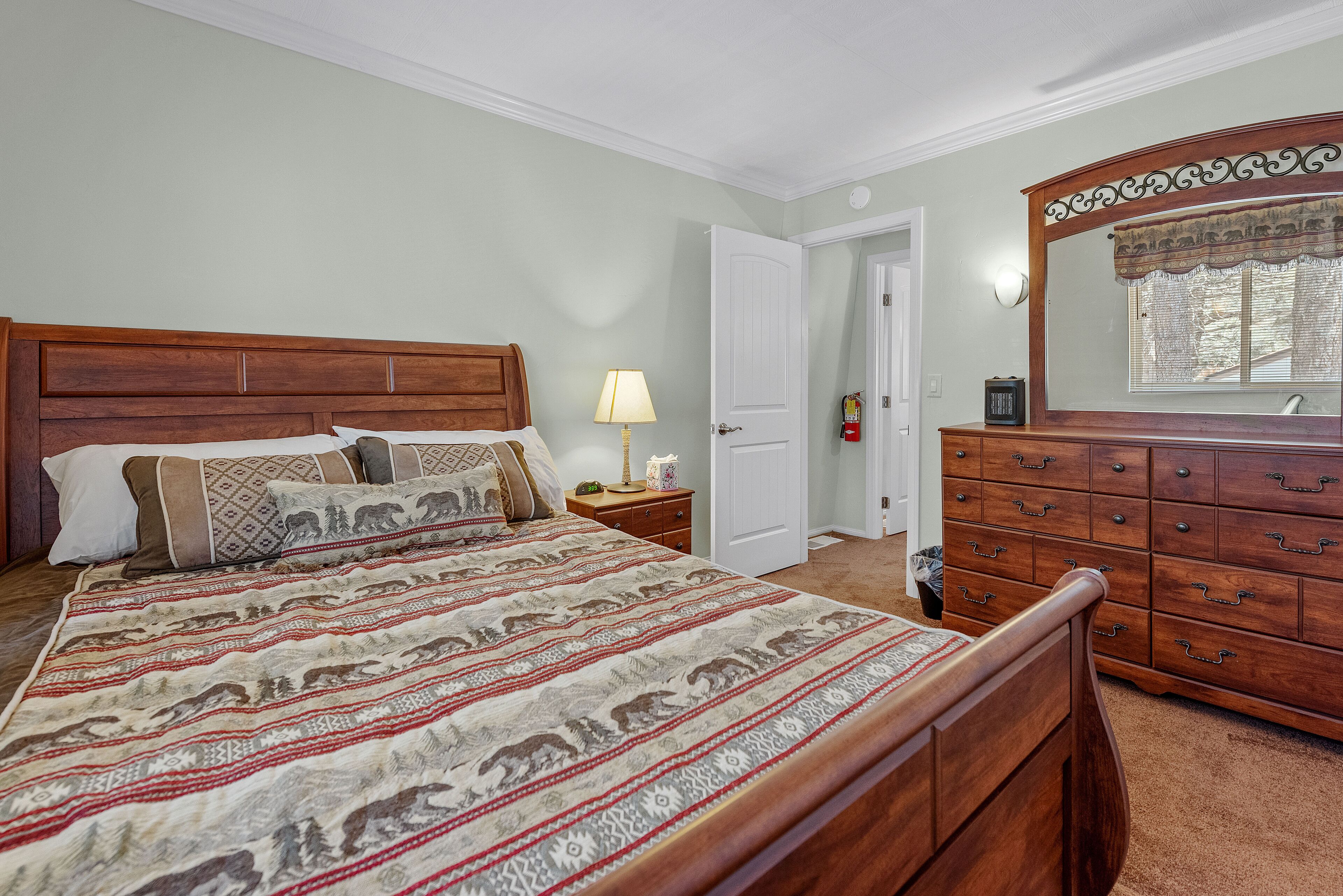 Une chambre à coucher avec un lit en bois, une table de chevet, une commode et un miroir.