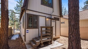 A two-story cabin with a wooden staircase leading to the entrance, surrounded by trees and a fenced yard. - KC's Haven - Relax with the whole family at this peaceful cabin. Smart TV, Fenced Yard (Sugarloaf)