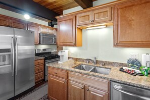 Una cocina moderna con electrodomésticos de acero inoxidable, armarios de madera y encimeras de granito, además de un lavavajillas integrado.