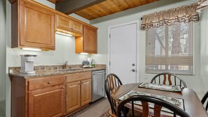 A kitchen with wooden cabinets, a built-in dishwasher, and a dining area with a table and chairs. - KC's Haven - Relax with the whole family at this peaceful cabin. Smart TV, Fenced Yard (Sugarloaf)