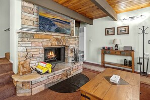 Una chimenea de piedra con fuego, una mesa de madera y una alfombra.