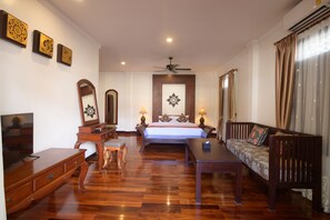 A hotel room with a bed, a sofa, a TV, a desk, and a ceiling fan.