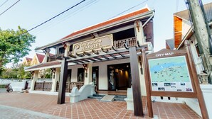 A hotel entrance with a signboard, a city map display, and a tiled pavement. - Lux hotel Luang Prabang (Luang Prabang)