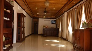 A spacious hallway with wooden cabinets, a television, and a chandelier. - Lux hotel Luang Prabang (Luang Prabang)