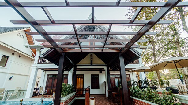 A covered outdoor area with a pool, wooden benches, and a brick wall. - Lux hotel Luang Prabang (Luang Prabang)