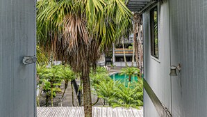 Uitzicht vanaf een balkon op een zwembad, palmbomen en een gebouw met balkons.