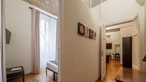A modern interior with a wooden floor, a bed, a dining table, and a wall with abstract art. - Castro Pretorio 3 - FromHometoRome (Roma)