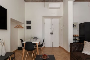 Un espacio habitable compacto con comedor, sofá, televisor y armario.