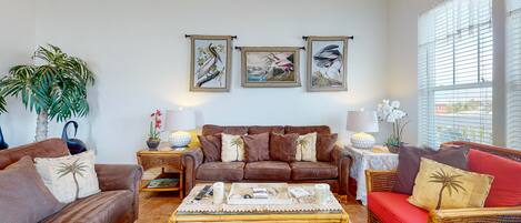A living room with a brown sofa, a red sofa, a coffee table, and a large potted plant.