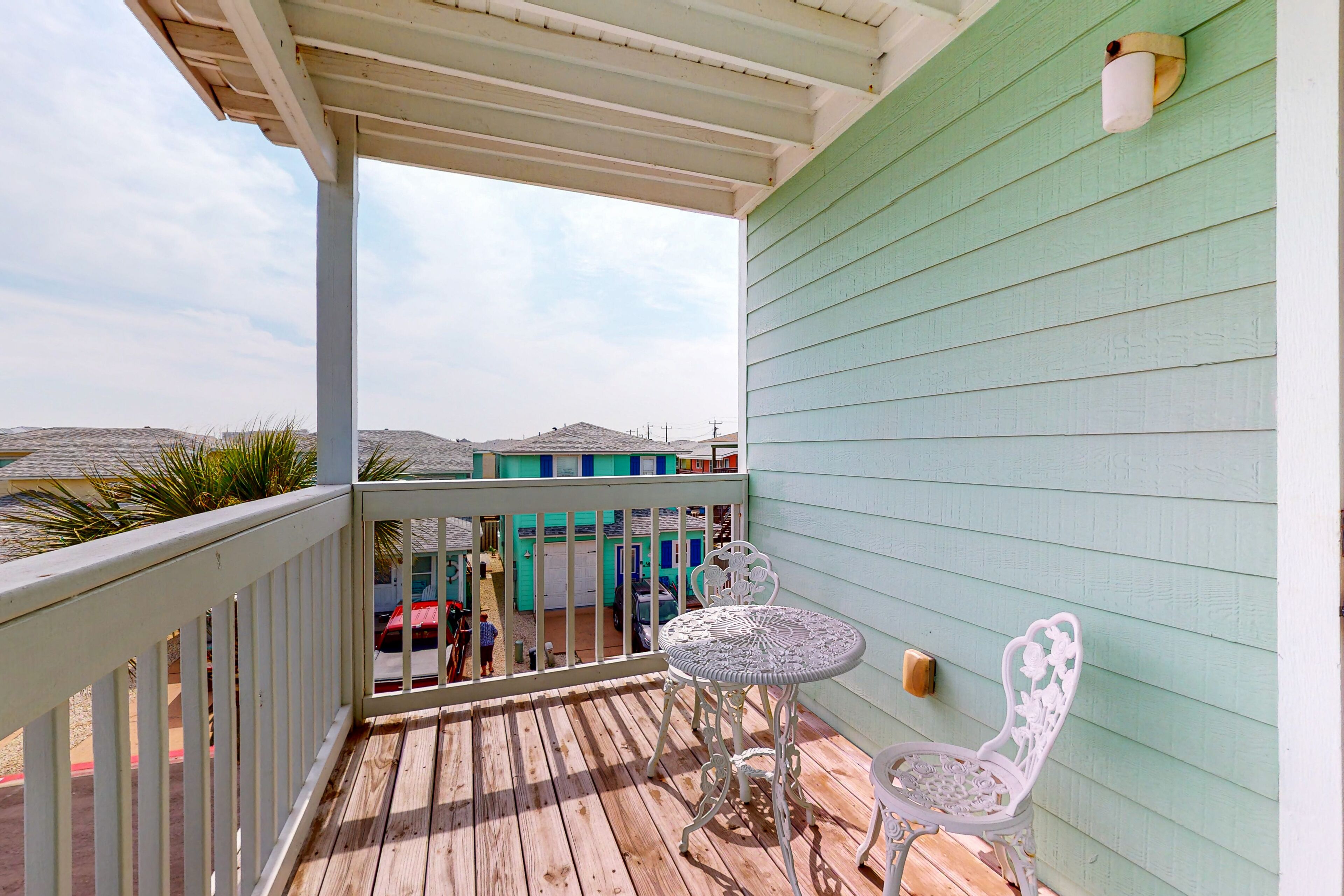 A wooden deck with a white railing, a small round table, and a white chair.