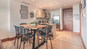 A modern kitchen with a dining area, featuring a wooden table and wicker chairs, a built-in oven, and a refrigerator. - Luxury Golf Front Apartment with Pool Access (Casa De Campo)