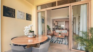 A dining area with a round wooden table, grey chairs, and a potted orchid. - Luxury Golf Front Apartment with Pool Access (Casa De Campo)