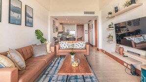 A spacious living room with a sofa, coffee table, and artwork on the walls. - Luxury Golf Front Apartment with Pool Access (Casa De Campo)