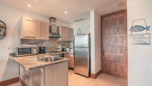 A modern kitchen with granite countertops, stainless steel appliances, and wooden cabinetry. - Luxury Golf Front Apartment with Pool Access (Casa De Campo)