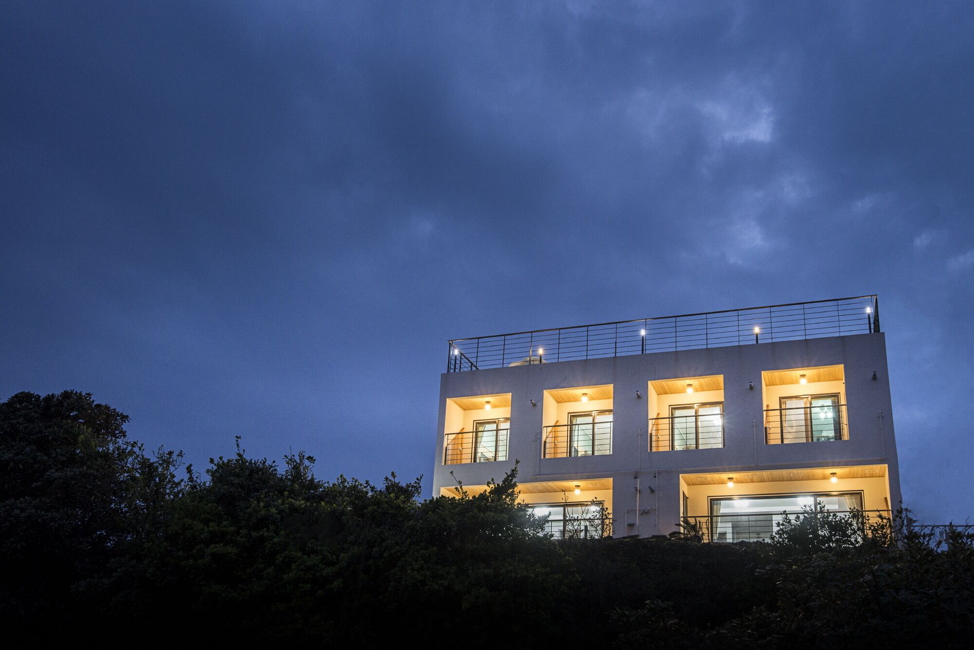 Un edificio moderno con varias ventanas y un balcón en la parte superior.