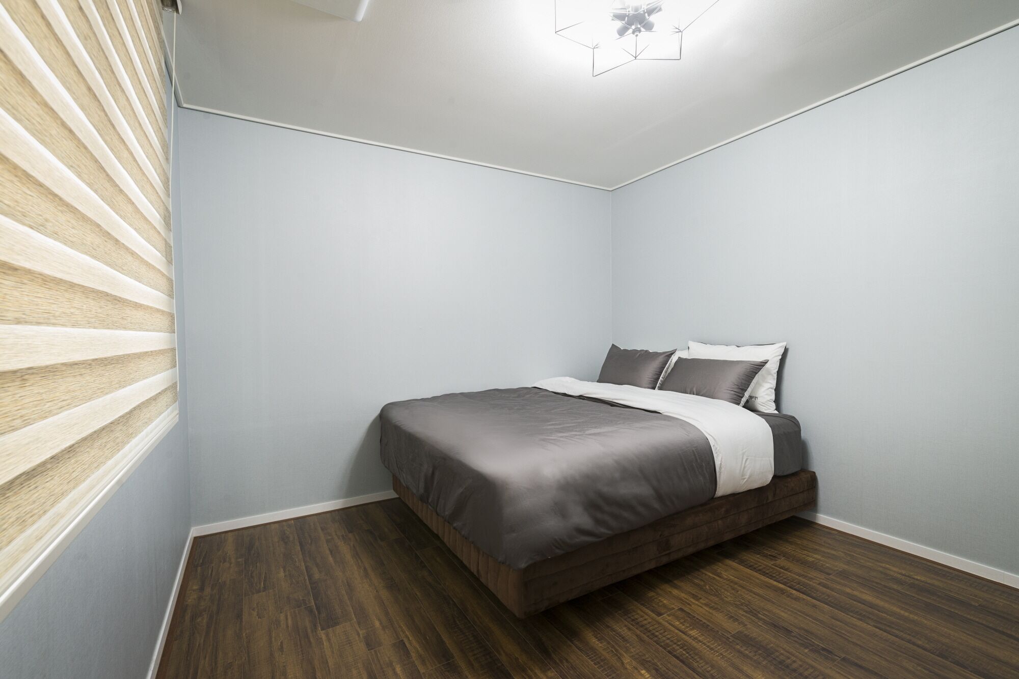Une chambre à coucher avec un lit, un plancher en bois et un ventilateur de plafond.