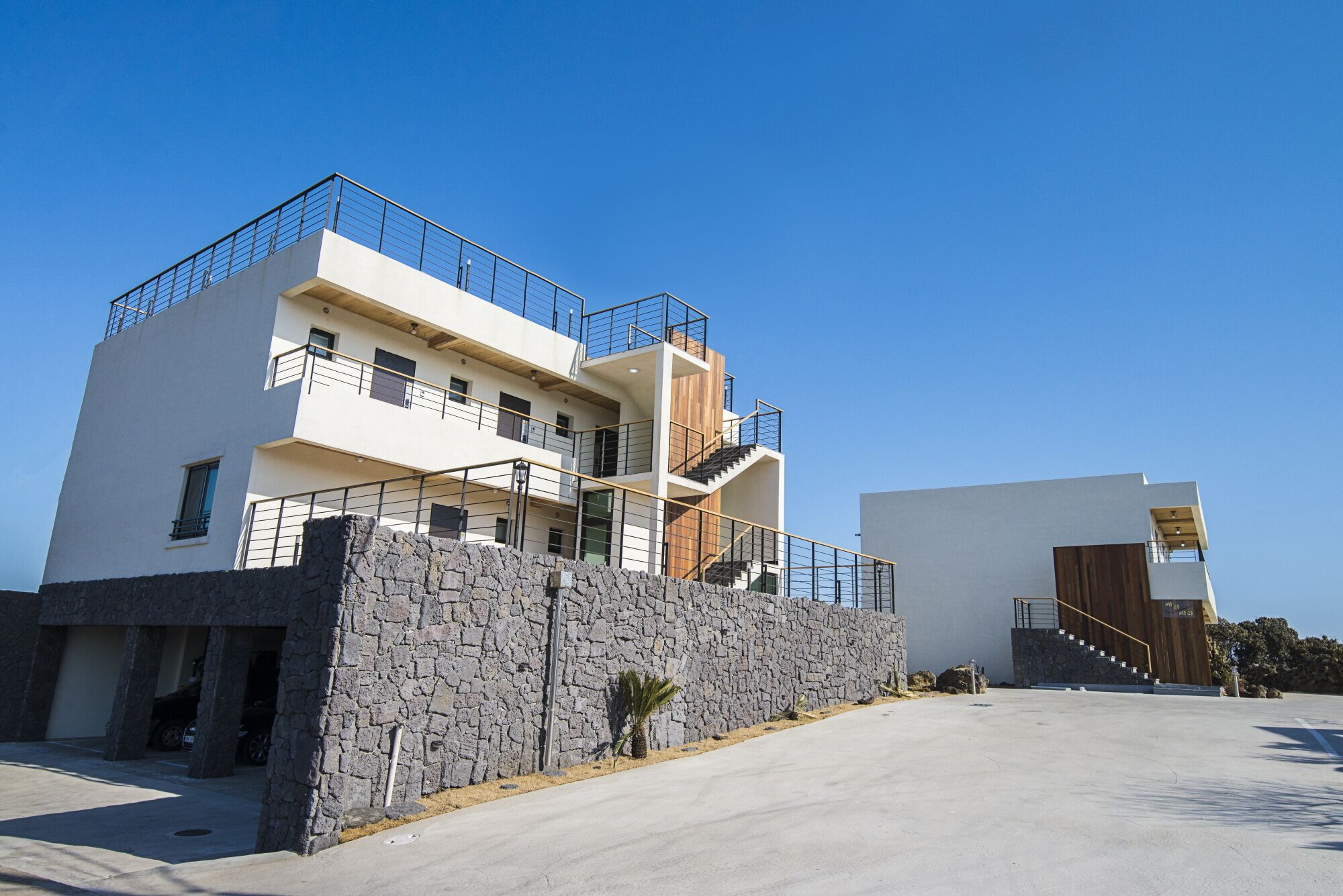 A modern multi-story building with a stone facade, multiple balconies, and a clear sky.