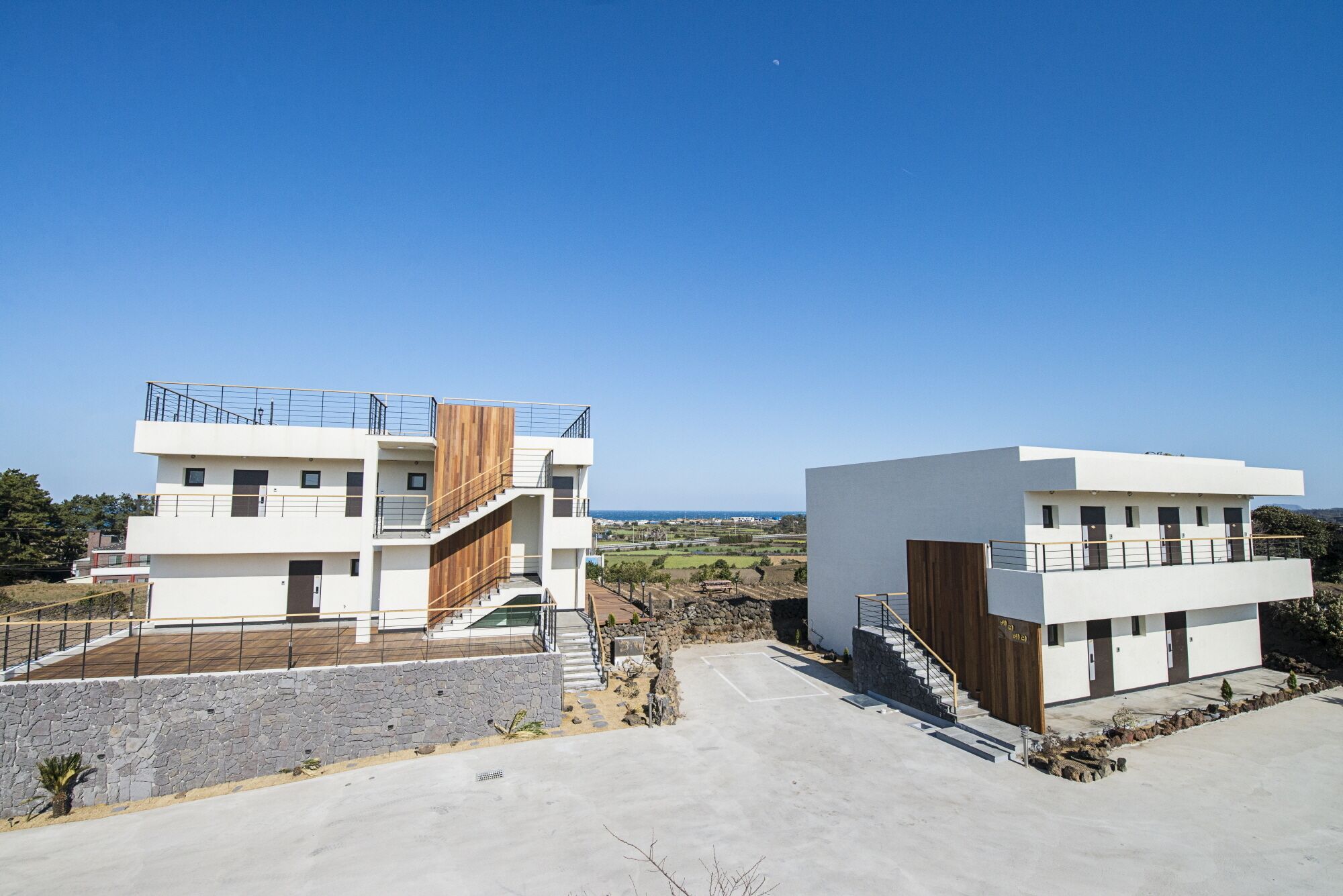 Two modern buildings with a clear view of the sea.
