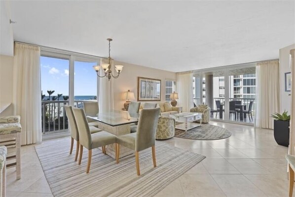 Relax in this open-plan living area with a dining and seating space, featuring a glass-top dining table and comfortable chairs.