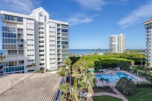 Situated in a lush, green area, this hotel offers a scenic view of a body of water and a well-maintained pool area.