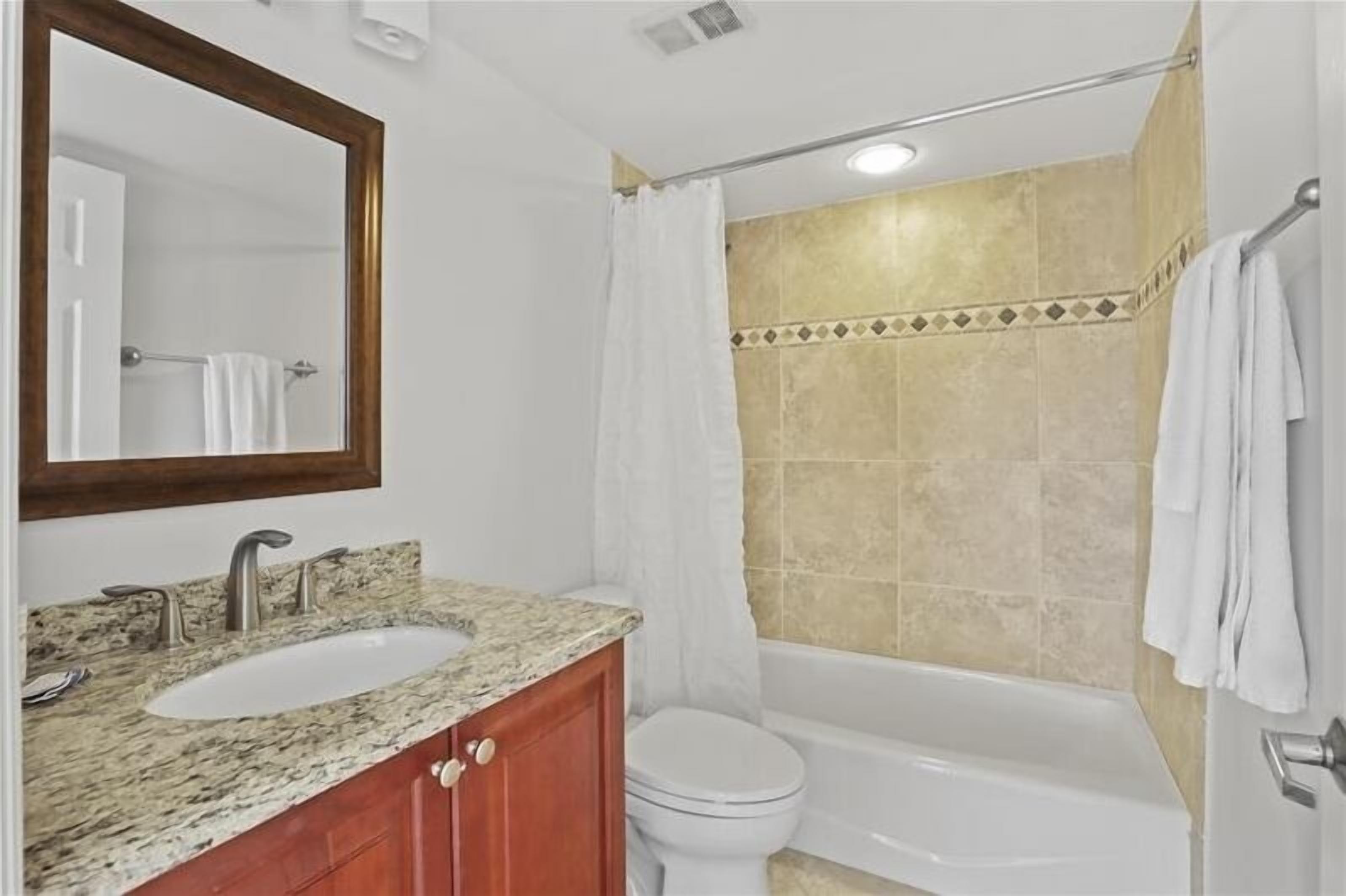 A bathroom with a sink, mirror, toilet, and bathtub.