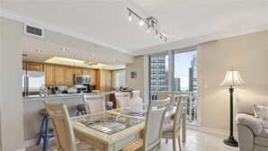 A modern kitchen with a dining area, large windows, and a view of the city.