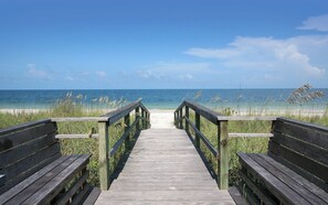 Un paseo marítimo de madera que lleva a una playa con vista despejada al océano.