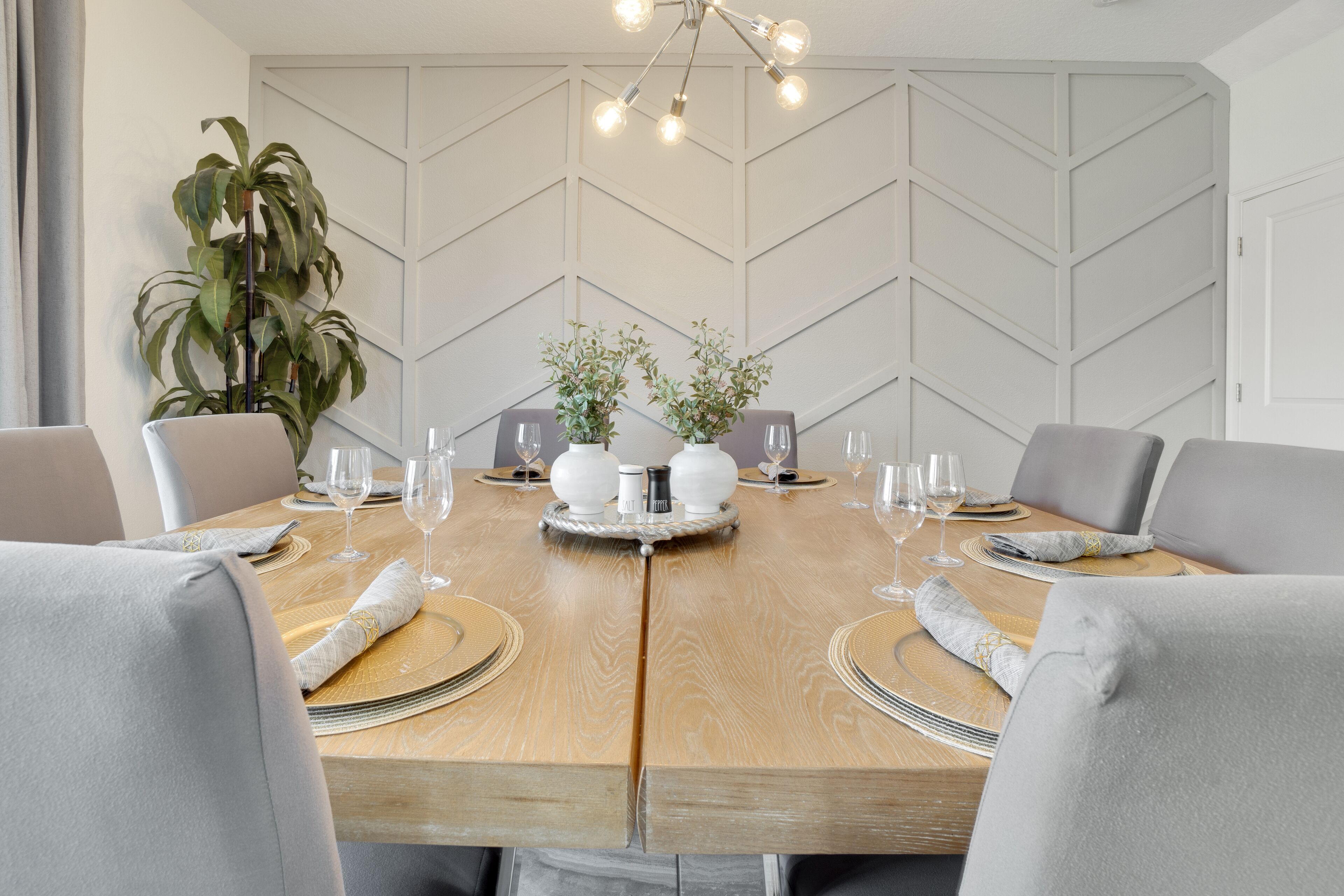 Mesa de comedor para seis personas, con un diseño geométrico moderno en la pared de fondo.