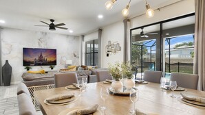A dining area with a wooden table set for six, surrounded by modern chairs. - Family Getaway near Disney, Private Pool, Theater, Game Room & Themed Bedrooms (Davenport)