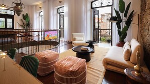 A spacious living room with a sofa, ottomans, a coffee table, and a TV. - Iconic double apartment with billar in front of the Arco Chato ruins  and pool (Ciudad de Panamá)