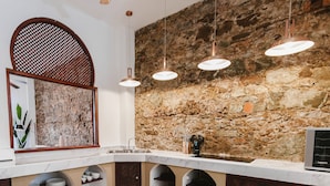 A kitchen with a stone wall, a sink, and overhead lighting. - Iconic double apartment with billar in front of the Arco Chato ruins  and pool (Ciudad de Panamá)