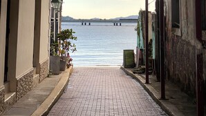 A narrow alleyway with a view of a calm body of water and a bridge in the distance. - Iconic double apartment with billar in front of the Arco Chato ruins  and pool (Ciudad de Panamá)