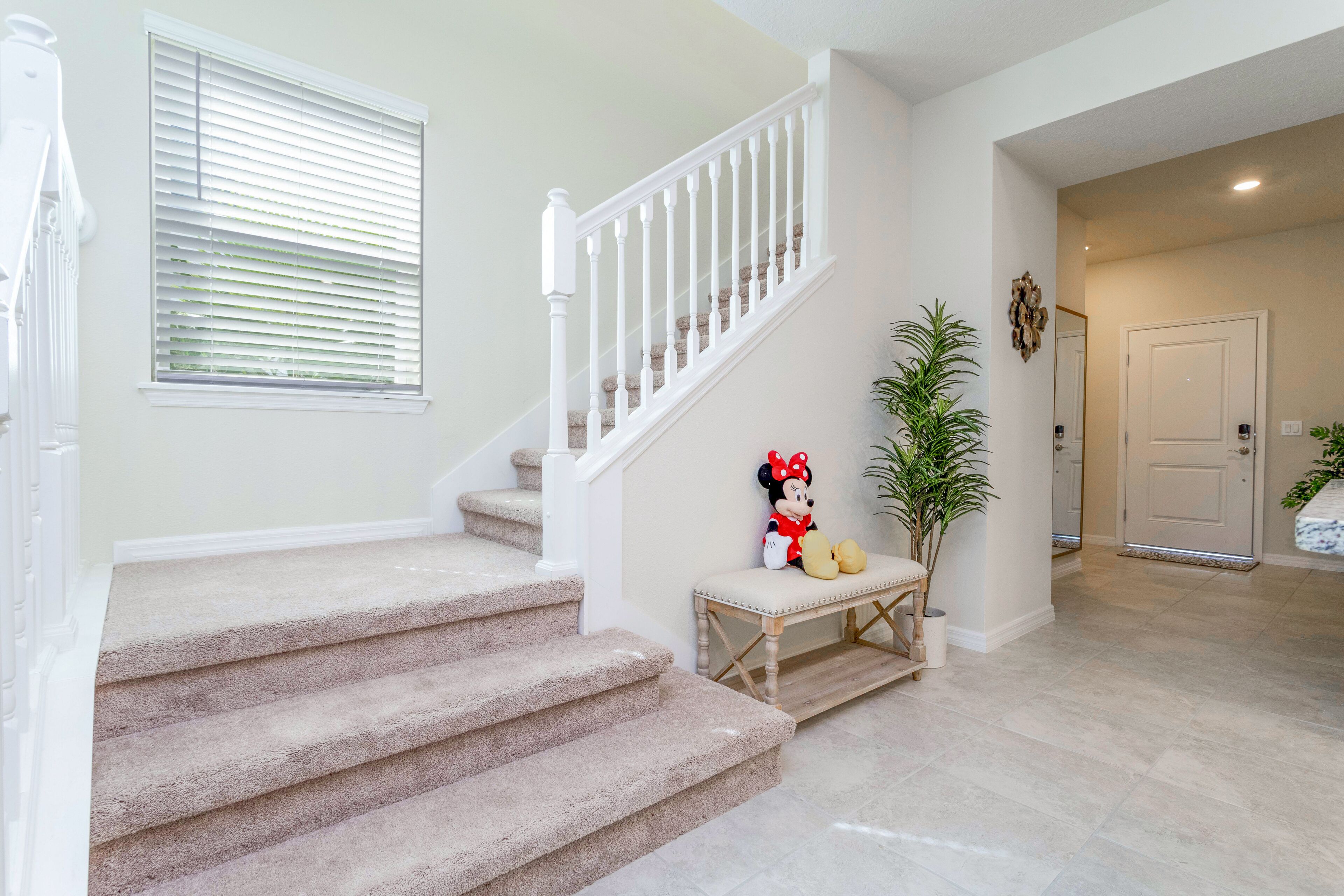 A carpeted staircase with white railings, a bench, and a Minnie Mouse plush toy.