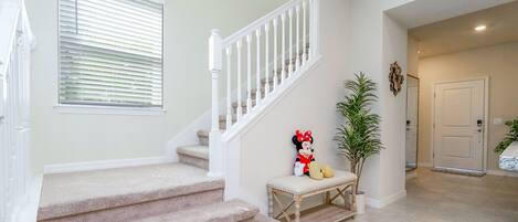 A carpeted staircase with white railings, a bench, and a Minnie Mouse plush toy.